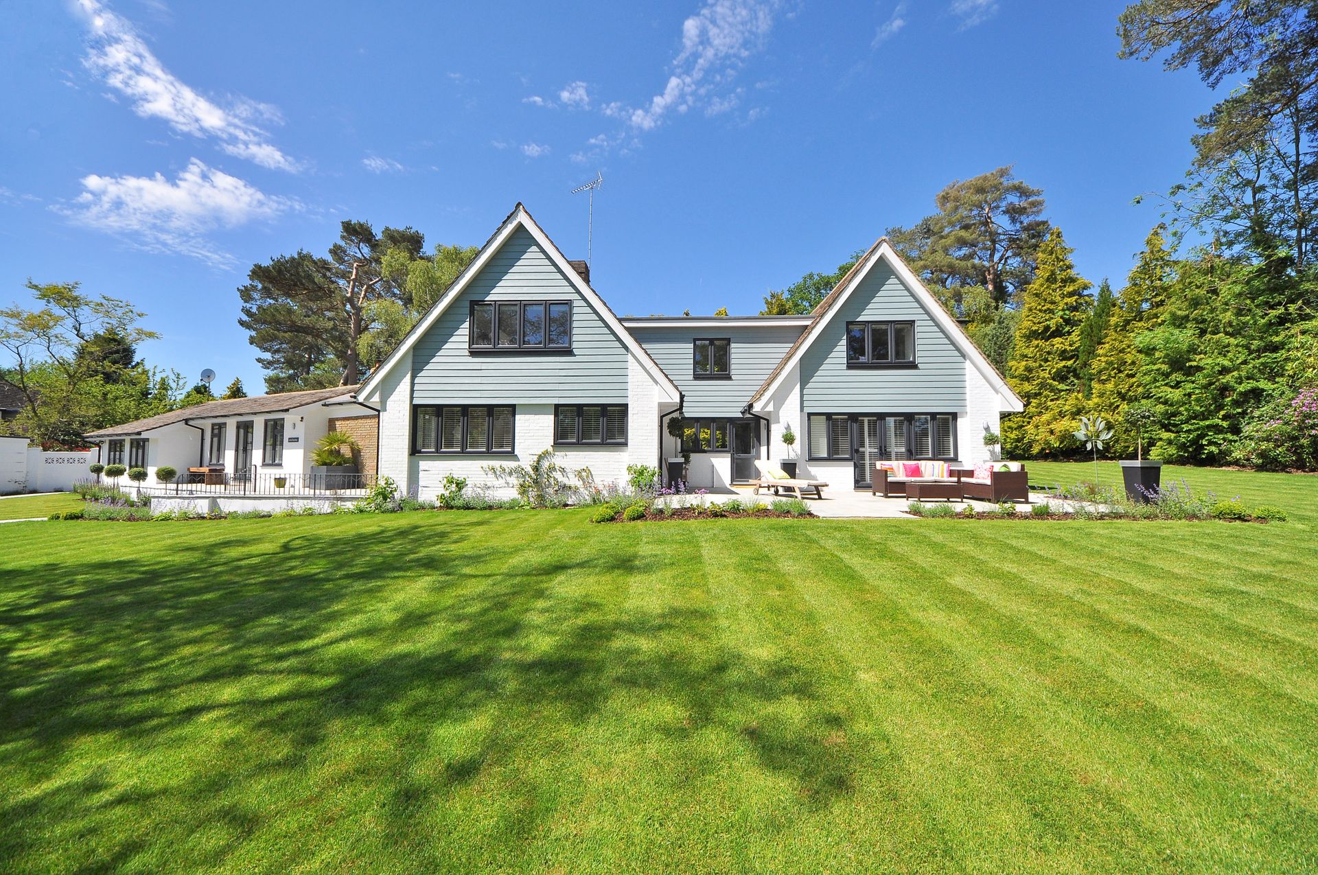 Striped freshly mowed lawn in front of a large white residential home